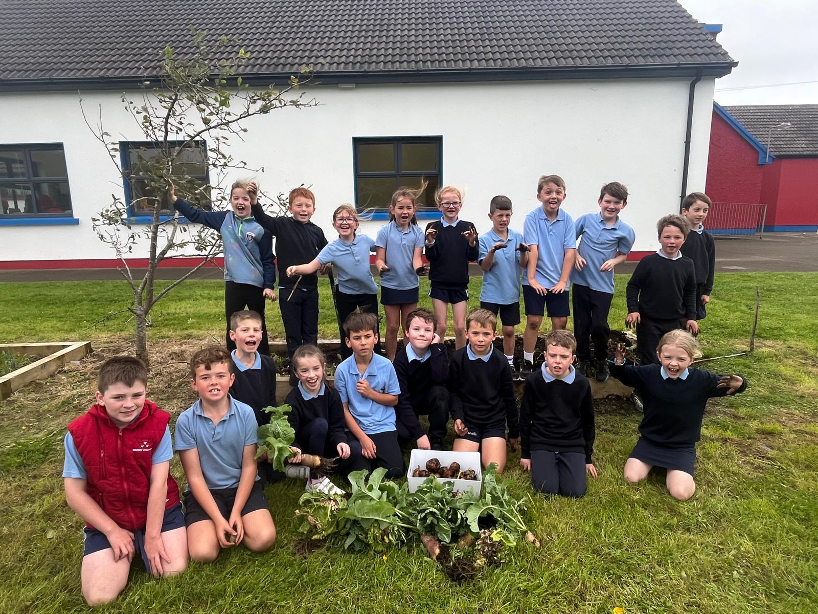 Pupils celebrating their vegetable harvest in the school garden